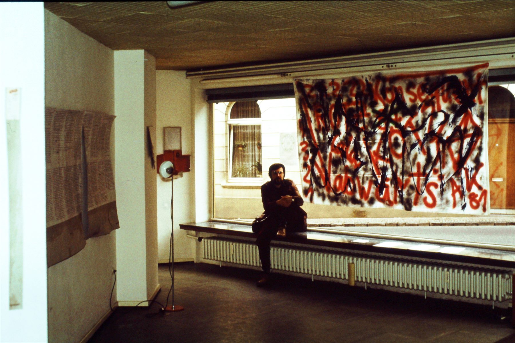 Person in einem frühen Klärwerk-Ausstellungsraum vor bemalter Stoffbahn