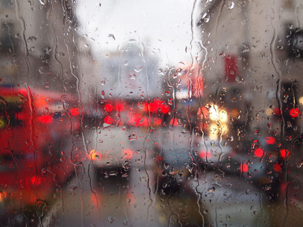 Piccadilly Circus durch eine regennasse Scheibe, rot dominierte Londoner Straßenszene